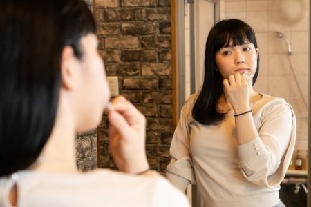 鏡の前で歯磨きする女性の画像