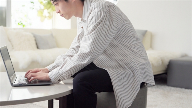 悪い姿勢でPC作業をする男性の画像
