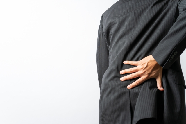 腰痛で腰を抑える男性の画像